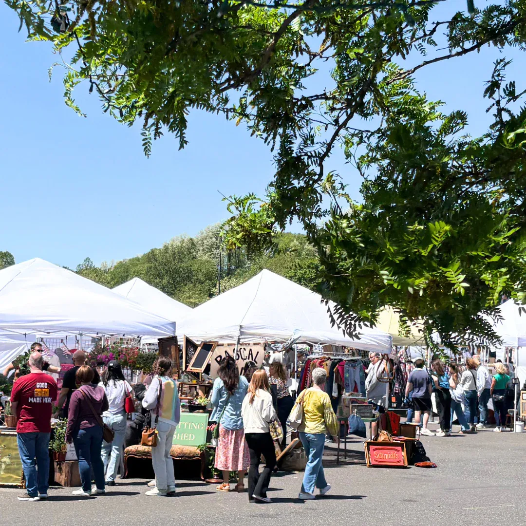 A crowd gathered at an outdoor art festival under white tents